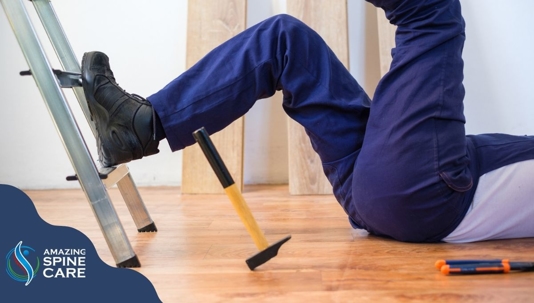 Worker on his back with one leg on ladder and other leg in the air.