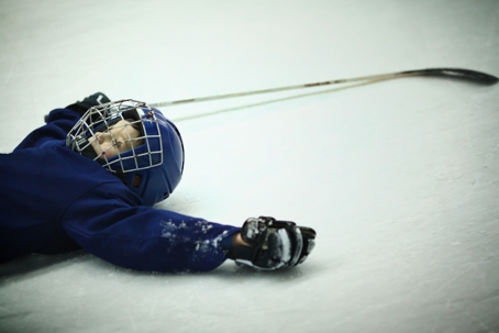 Concussions in winter sports can result from situations like depicted here where a kid playing hockey lays on hard ice