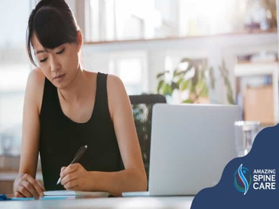 A woman sits at a desk writing